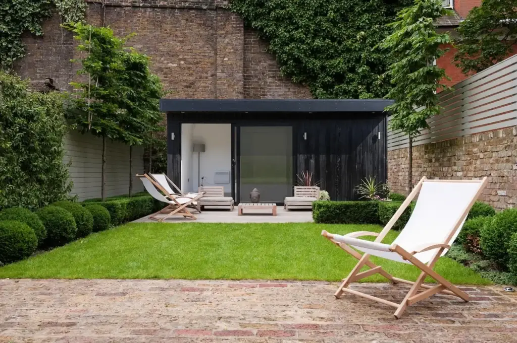 Black wood clad garden room at the bottom of a garden.