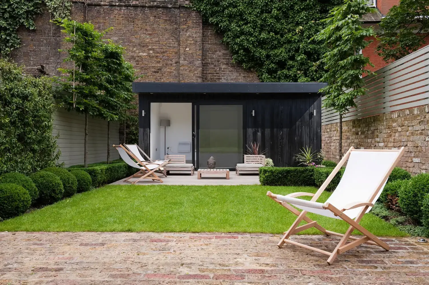 Black wood clad garden room at the bottom of a garden.