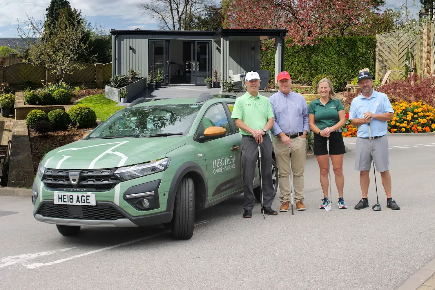Image of 4 people in front of a car with a garden studio in the background.