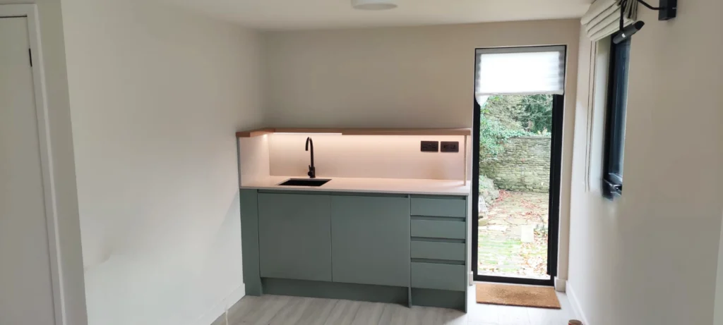 Compact ensuite bathroom with electric shower, toilet, and basin inside Sheffield garden room annexe