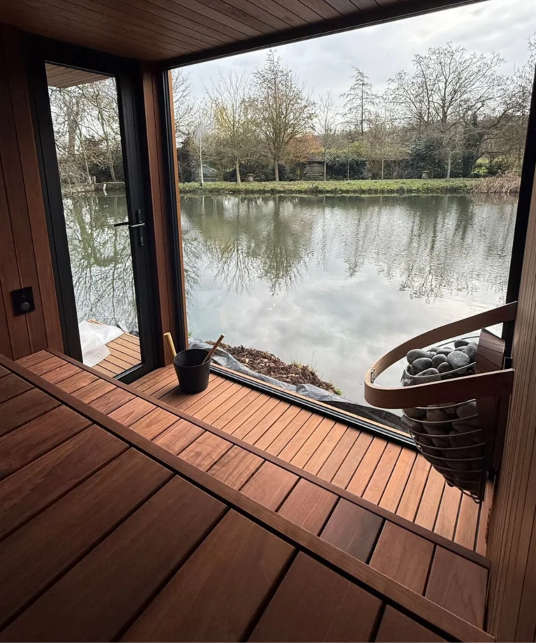 Luxury outdoor sauna interior with panoramic glass window overlooking a lake